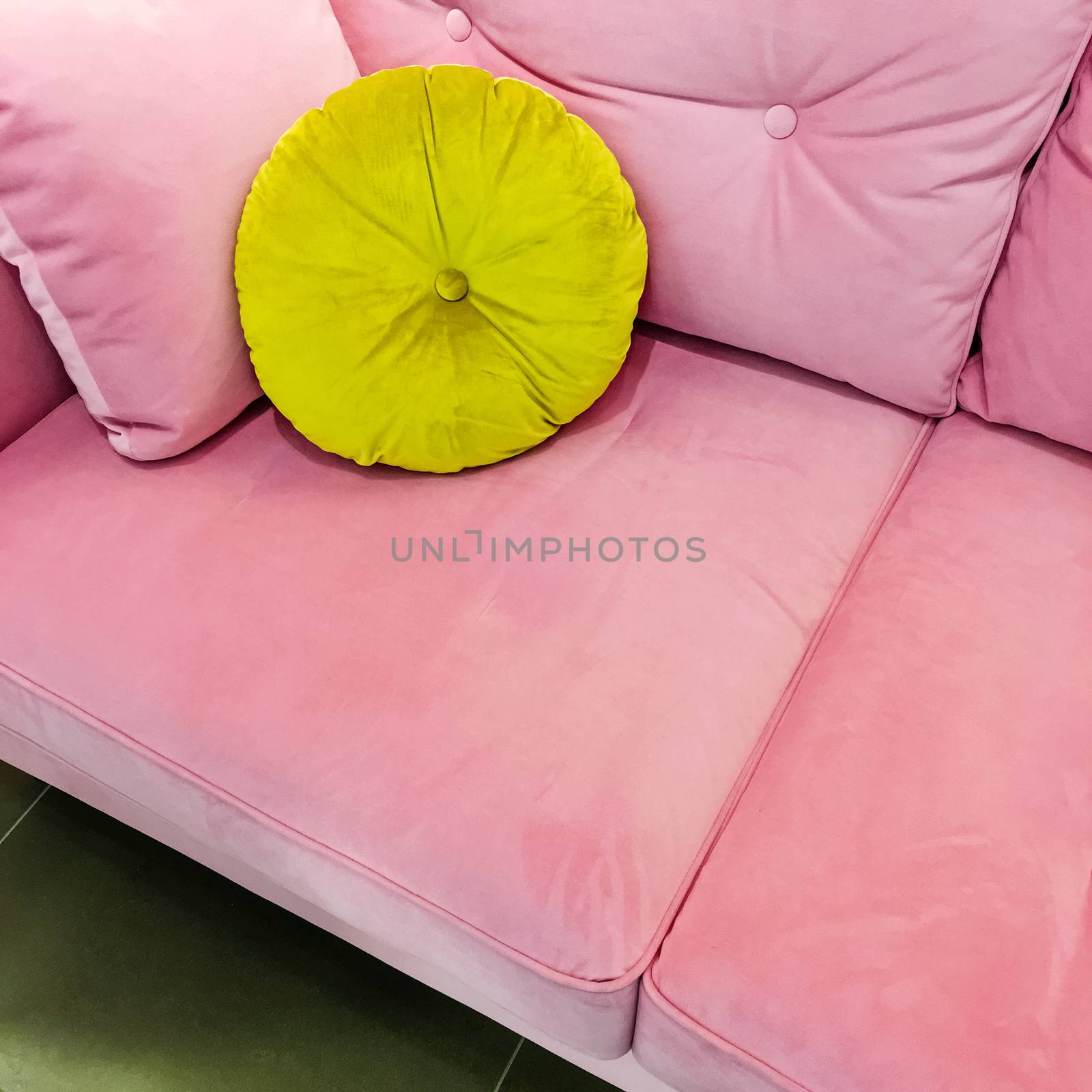 Pink velvet sofa with fancy lime green cushion. Luxurious furniture.