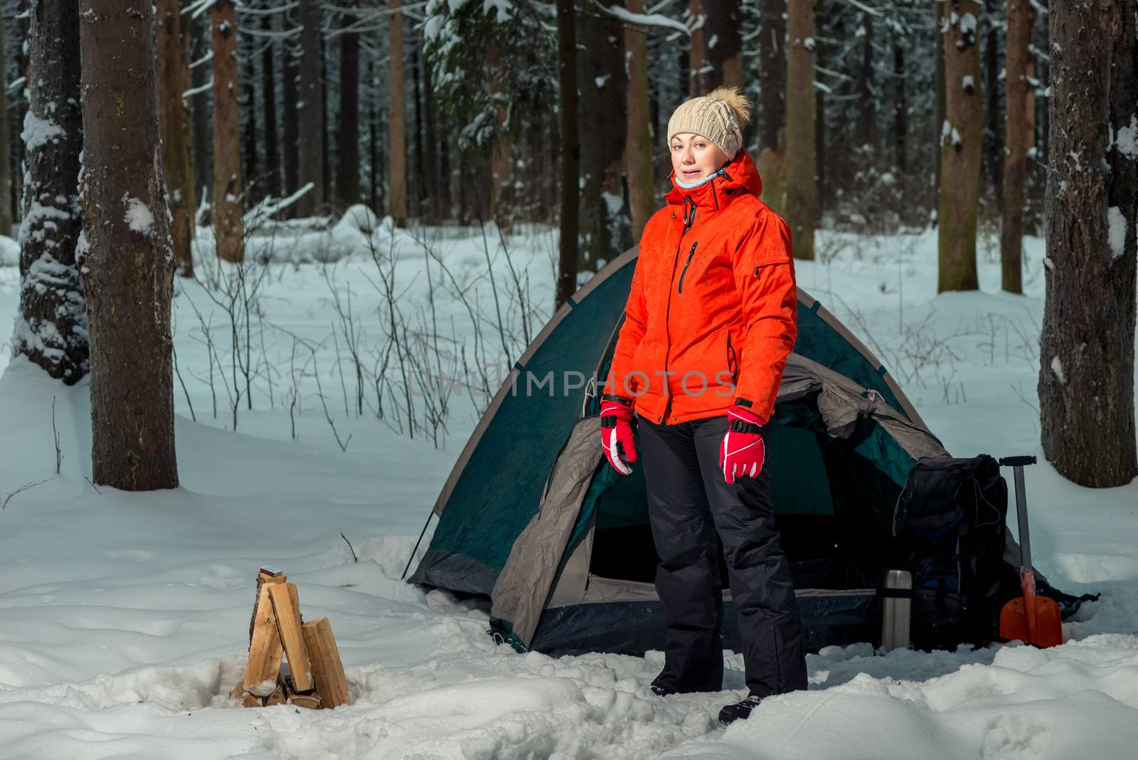 woman near a tent at a camping site in a winter forest in the mountains