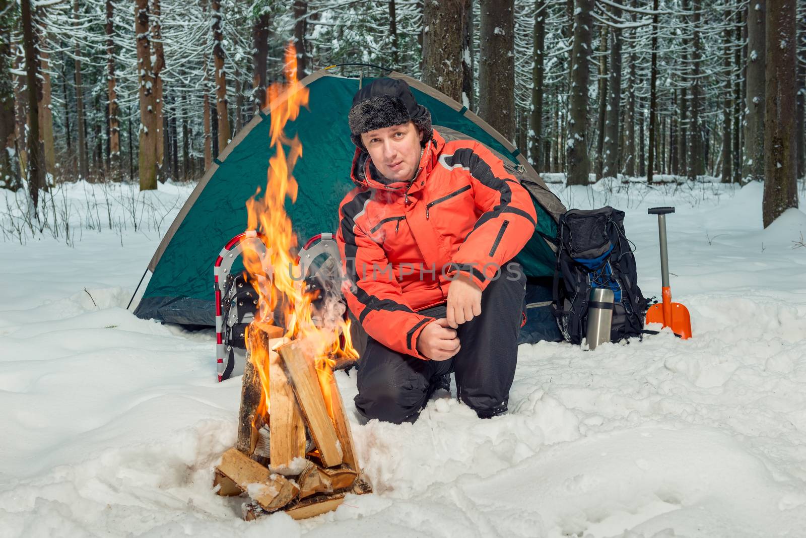 a tourist in a winter forest in extreme conditions is building a fire