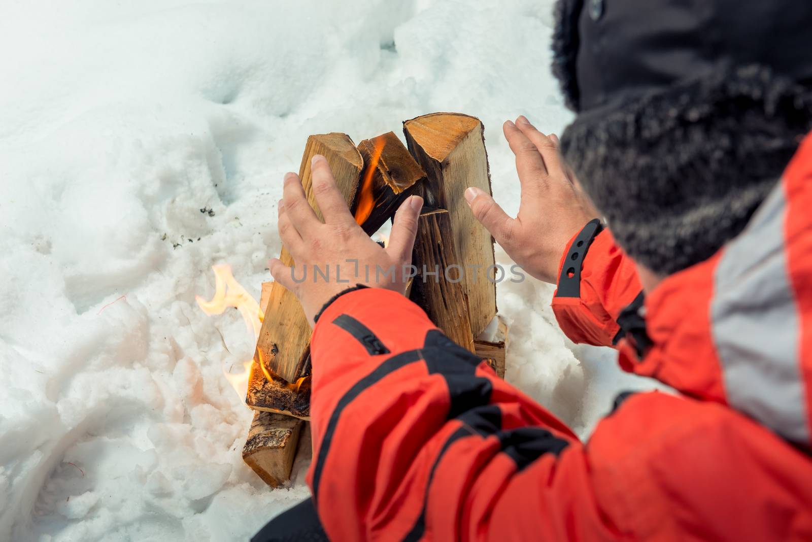 close-up photo - tourist warms his hands near the fire in the wi by kosmsos111