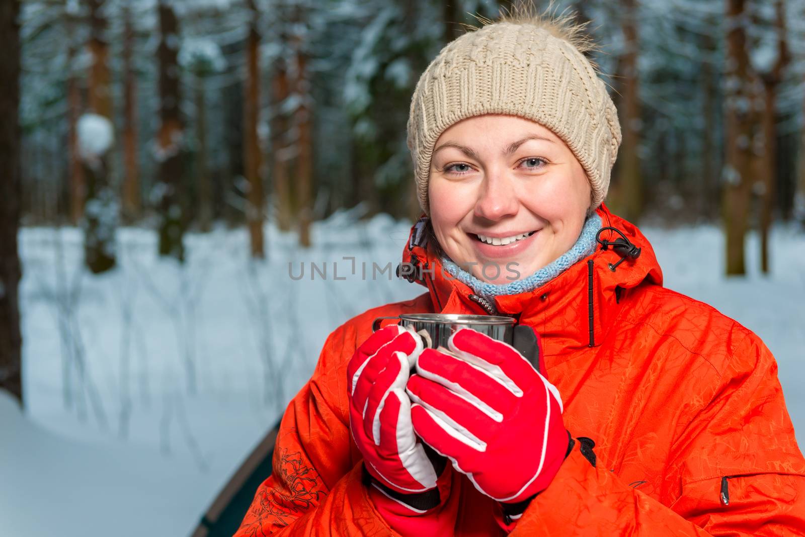happy girl with a mug of tea in a winter forest