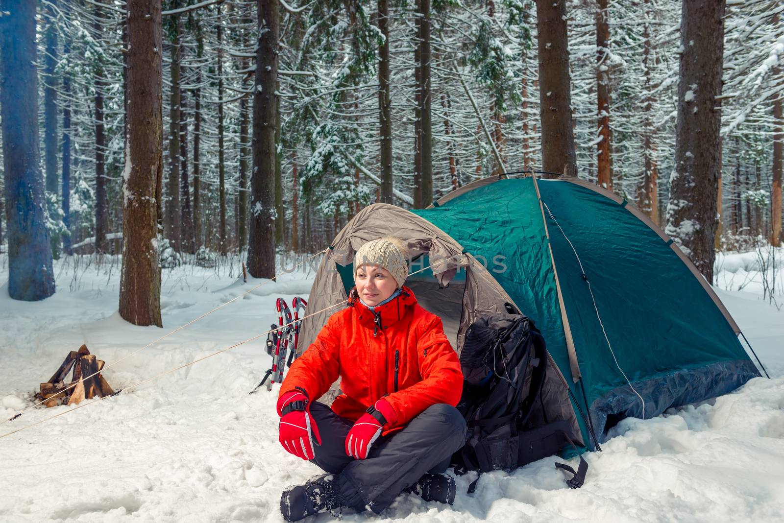 relaxed tourist woman sitting near a tent in a winter forest by kosmsos111