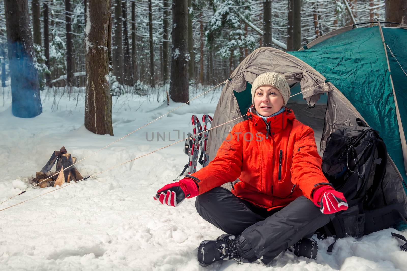 Young active tourist on a campaign sits near a tent in the winte by kosmsos111