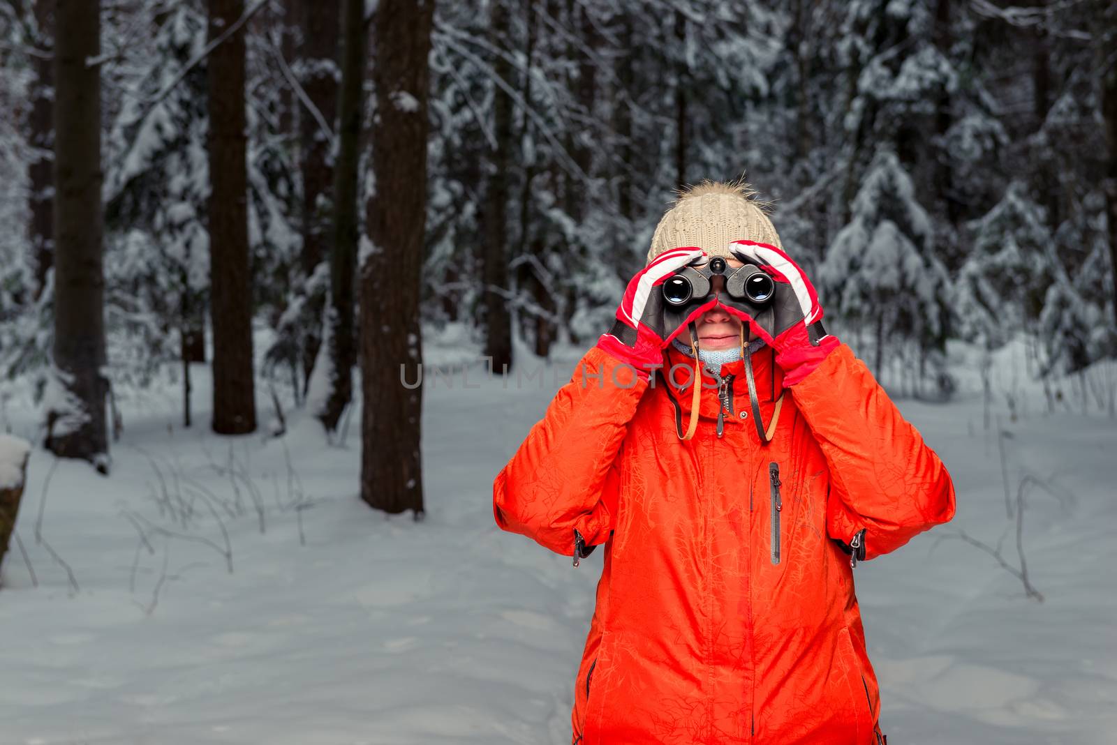 woman tourist with binoculars in the winter forest