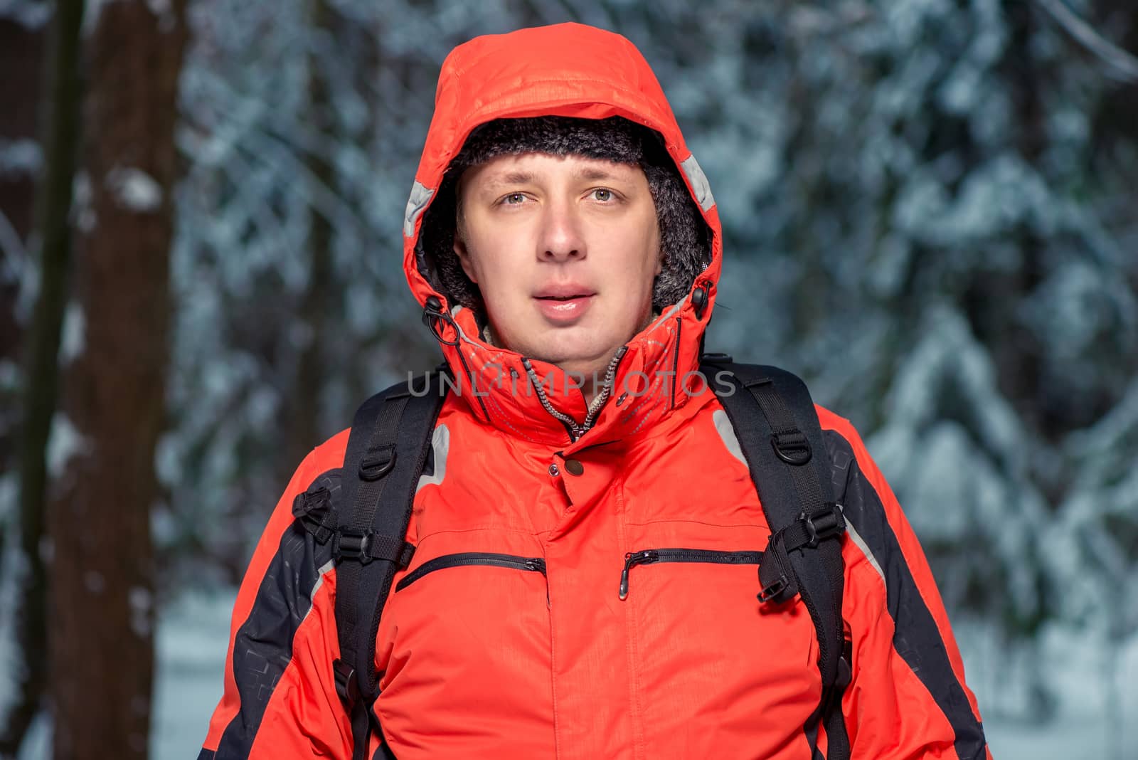 man in a jacket on a hike with a backpack in the winter forest