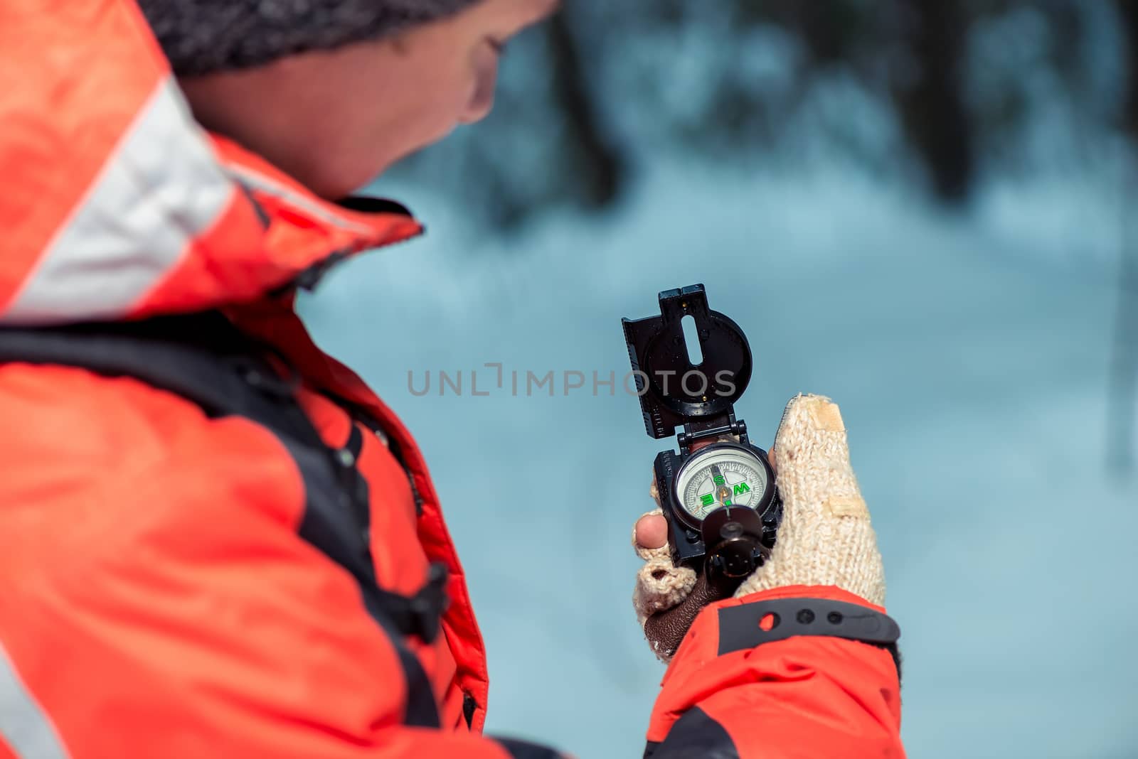 tourist checks the route with a compass in the winter forest