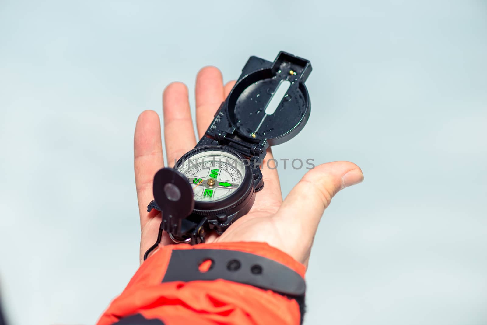 man's hand close-up with a compass on white snow background