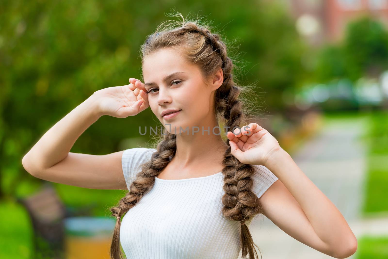 charming girl with two braids close-up portrait in the park