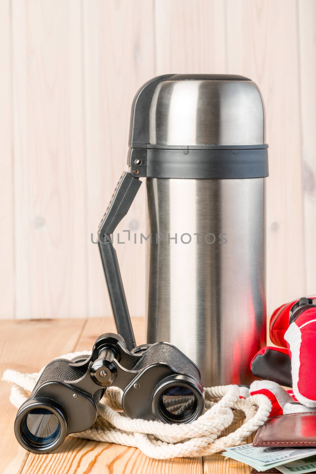 thermos with hot tea, binoculars, rope and gloves for a dangerous winter hike on a wooden background