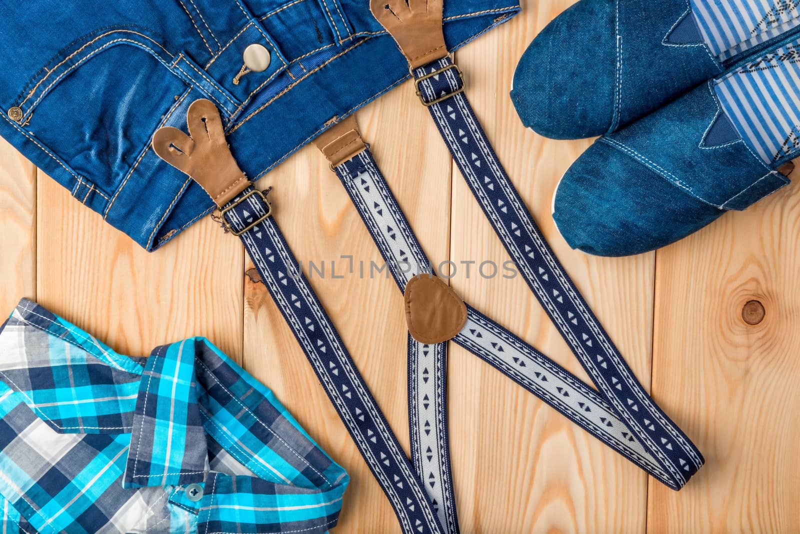 check shirt, jeans, shoes and suspenders on a wooden background top view - clothes for a boy