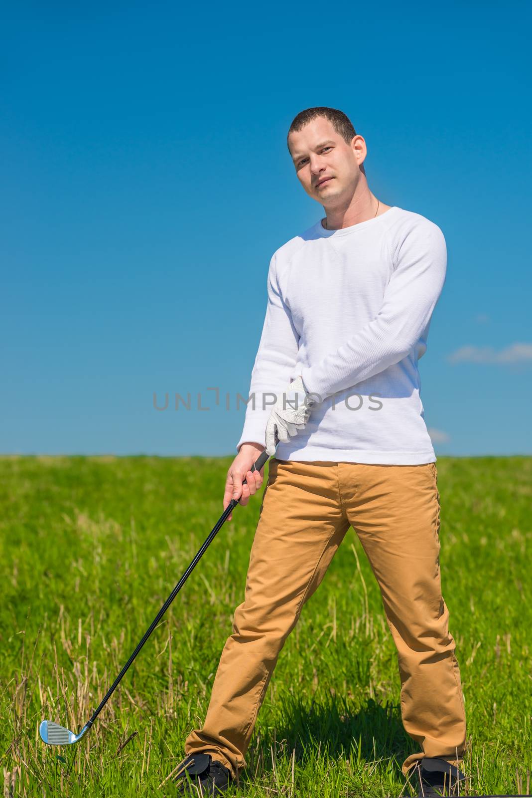 golfer with a golf club on a green field on a sunny day