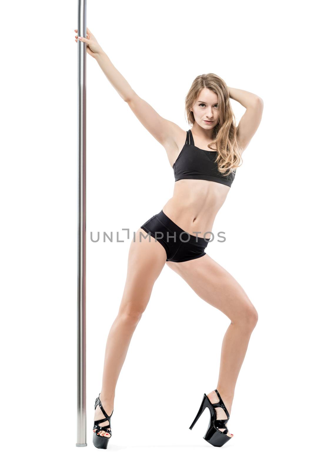 slender charming woman dancing near a pylon in sports underwear and shoes on a white background