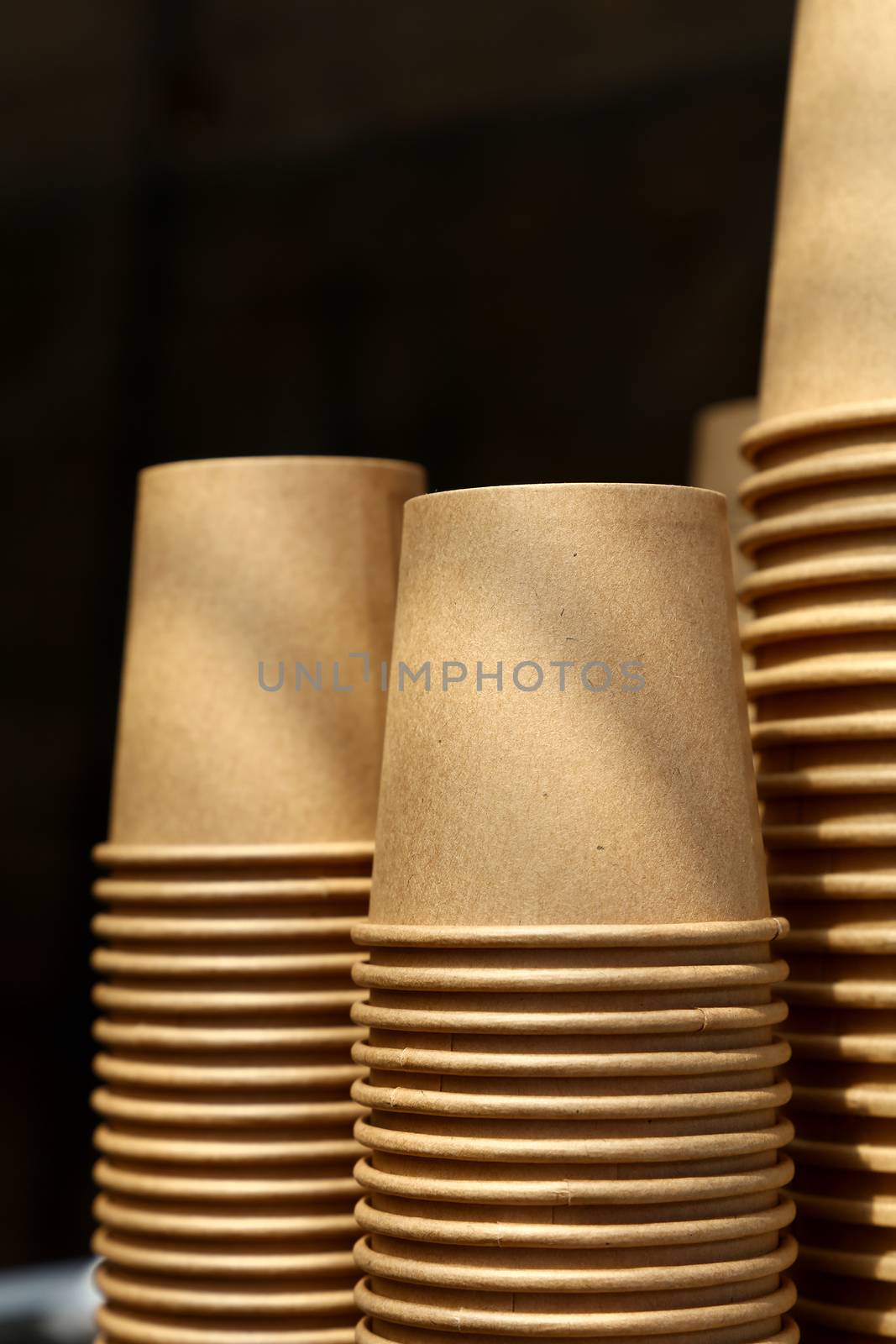 Close up stack of brown disposable kraft paper cups on coffee machine, low angle view