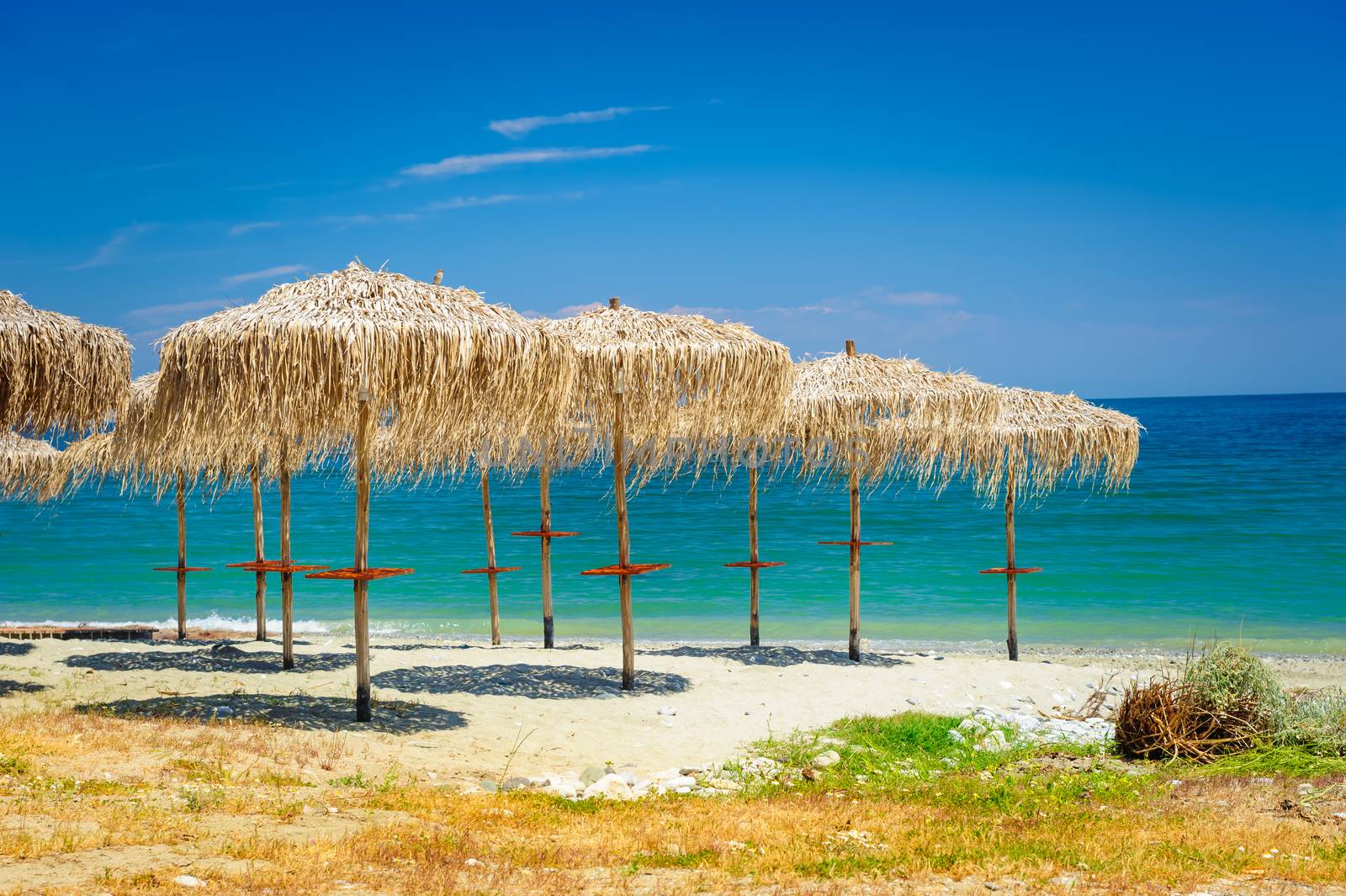 reed umbrellas at empty beach by starush