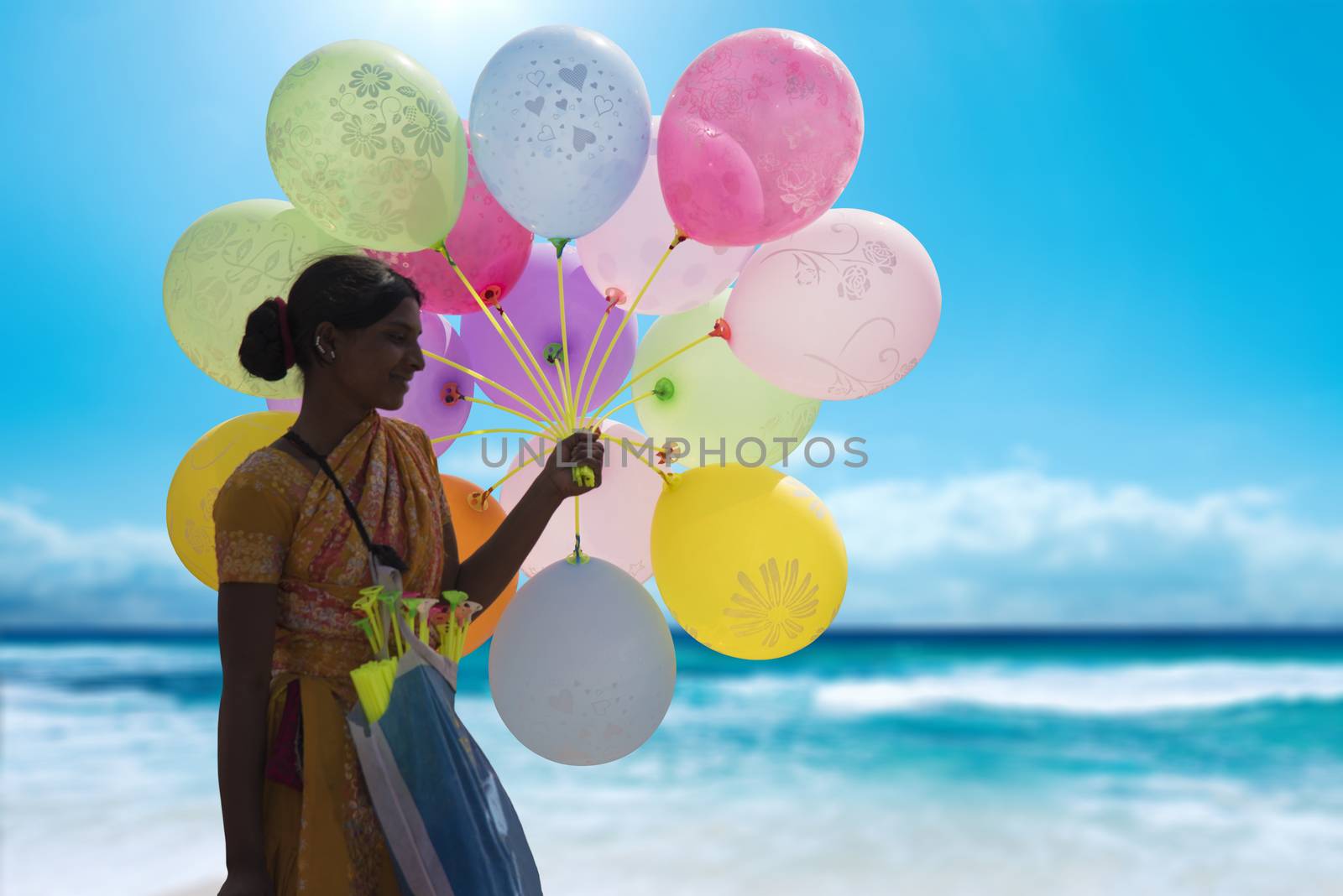 Indian hawker holding a bunch of colorful balloons at a beach and selling them to make a living.