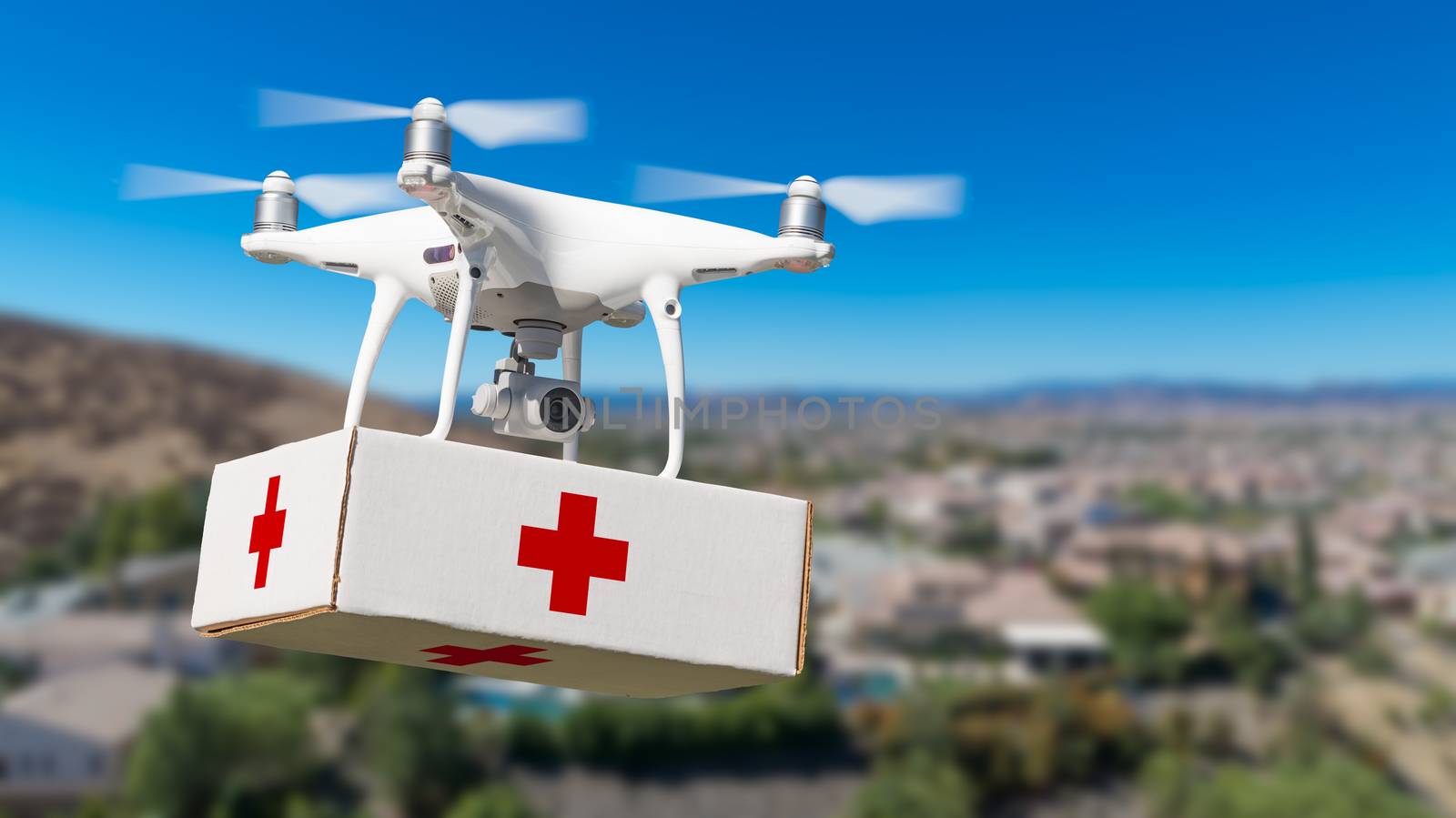 Unmanned Aircraft System (UAS) Quadcopter Drone Carrying First Aid Package Over Neighborhood.