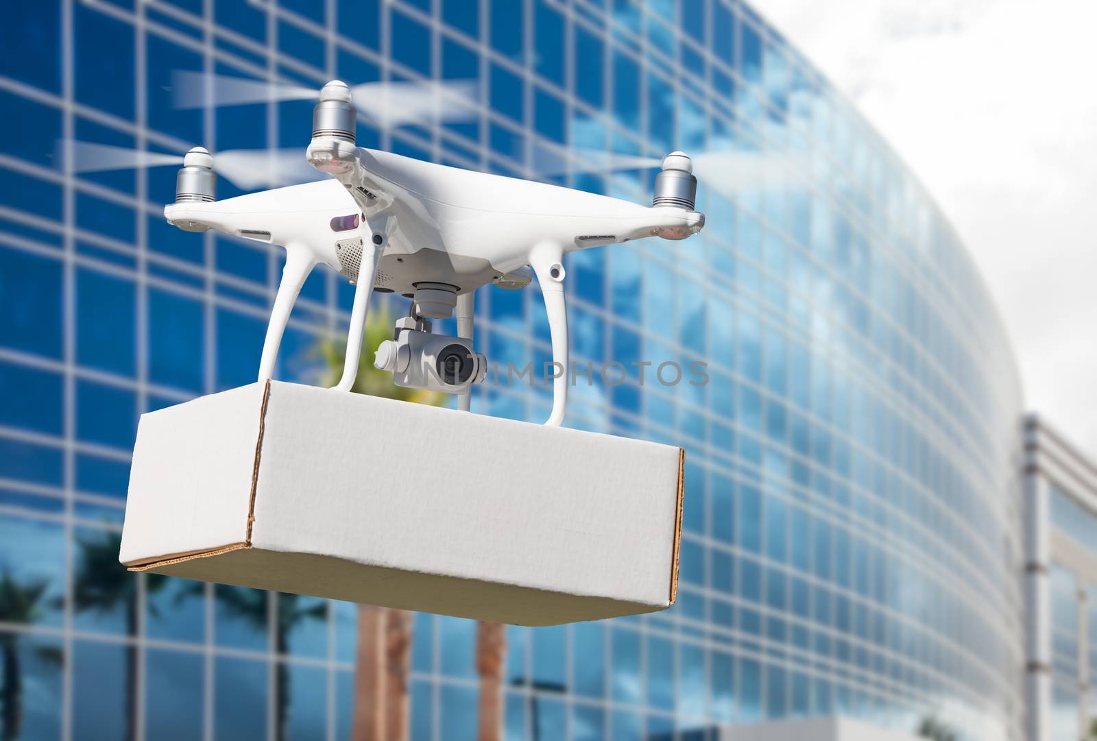 Unmanned Aircraft System (UAS) Quadcopter Drone Carrying Blank Package Near Corporate Building. by Feverpitched