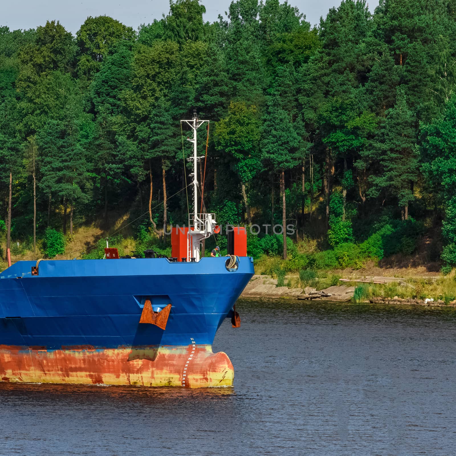 Blue cargo ship with long reach excavator moving to the port