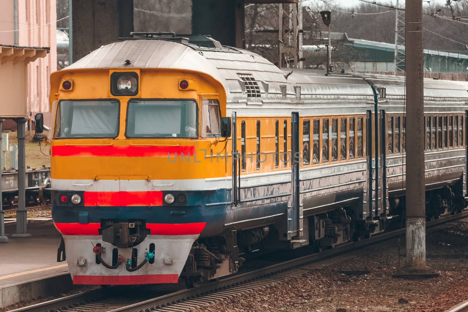 Old yellow passenger diesel train moving at the terminal