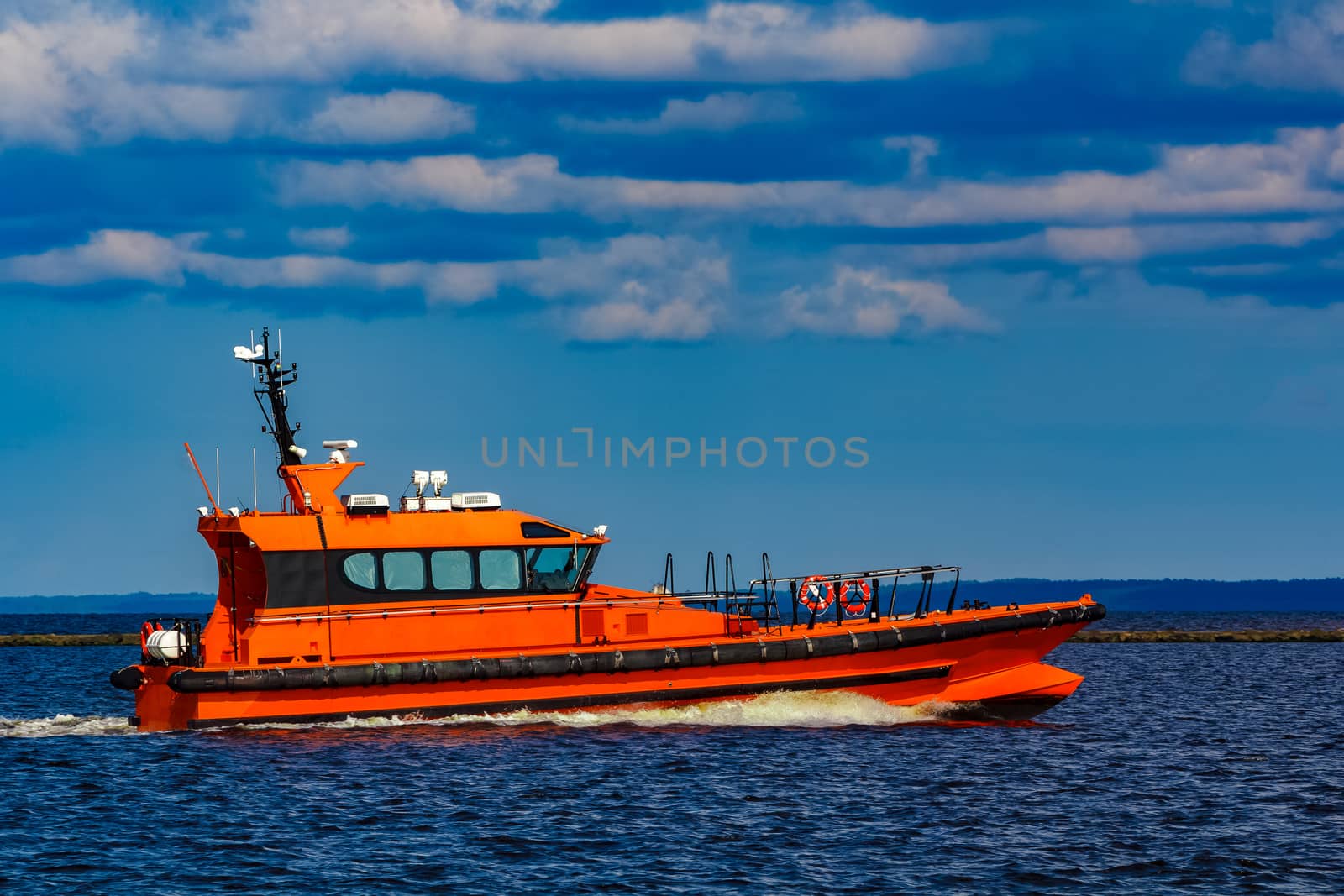 Orange pilot boat moving by the river in Europe. Rescue service