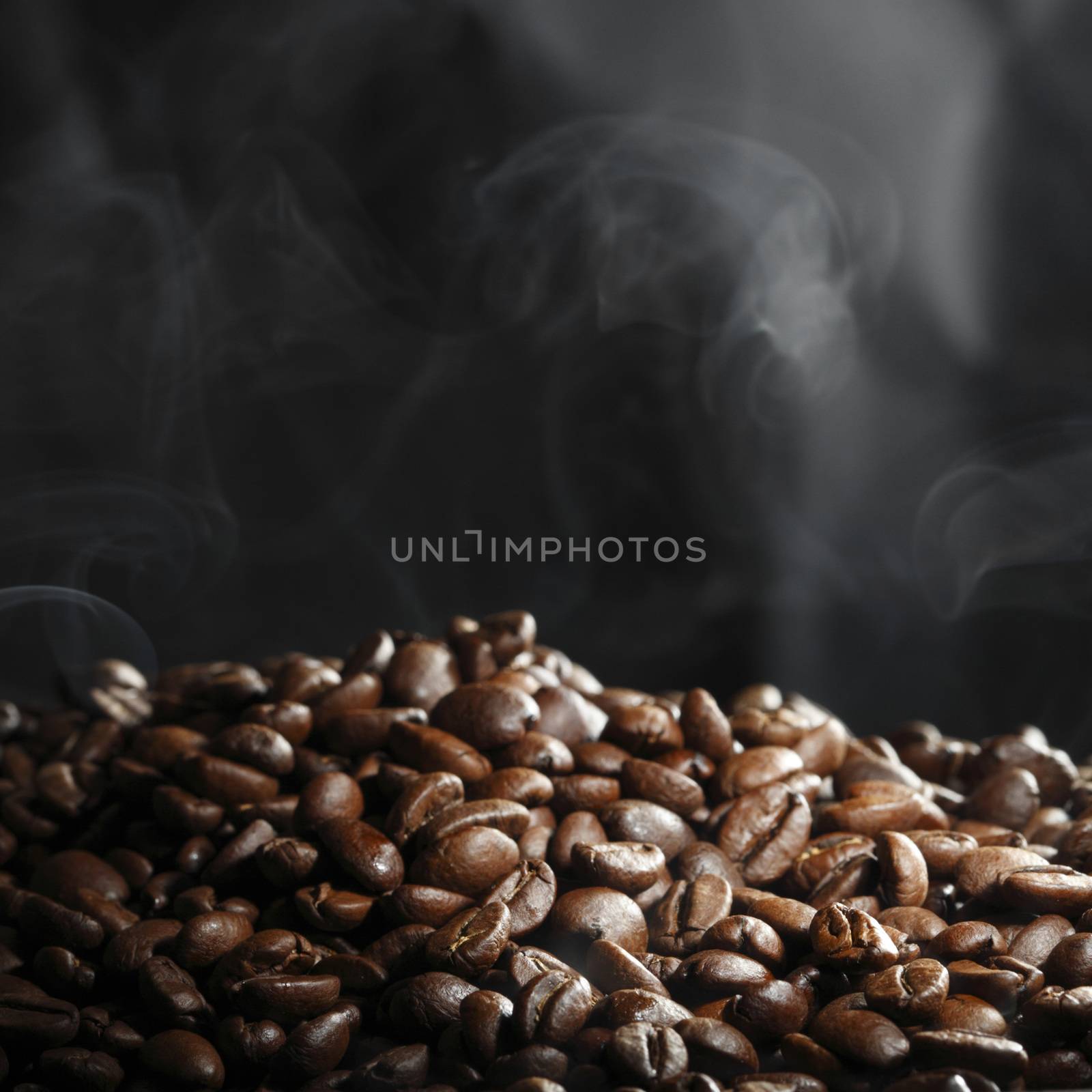 Hot roasted coffee beans and steam on black