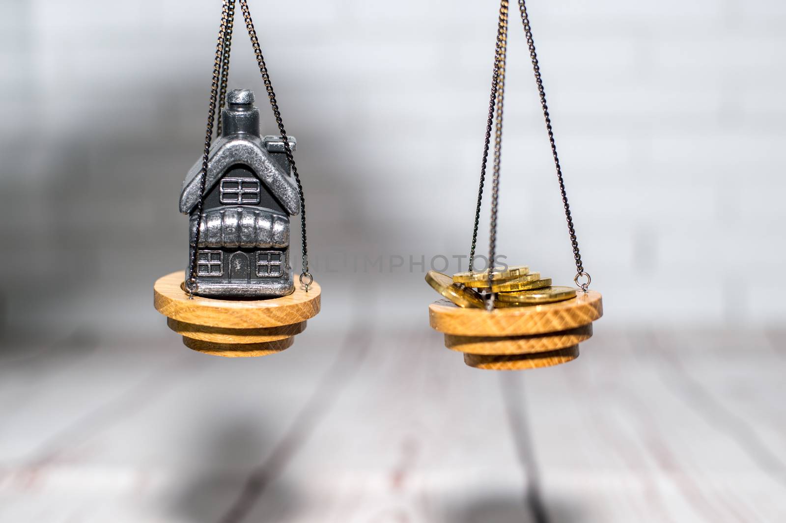 Stack of coins and a small house on the scales. The concept of choice, cash savings and purchase of real estate