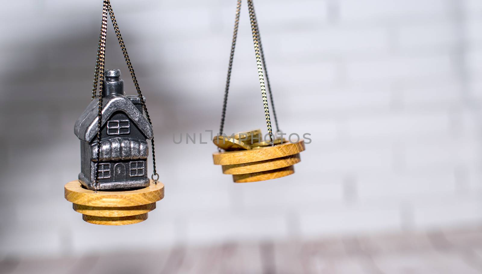 Stack of coins and a small house on the scales. The concept of choice, cash savings and purchase of real estate