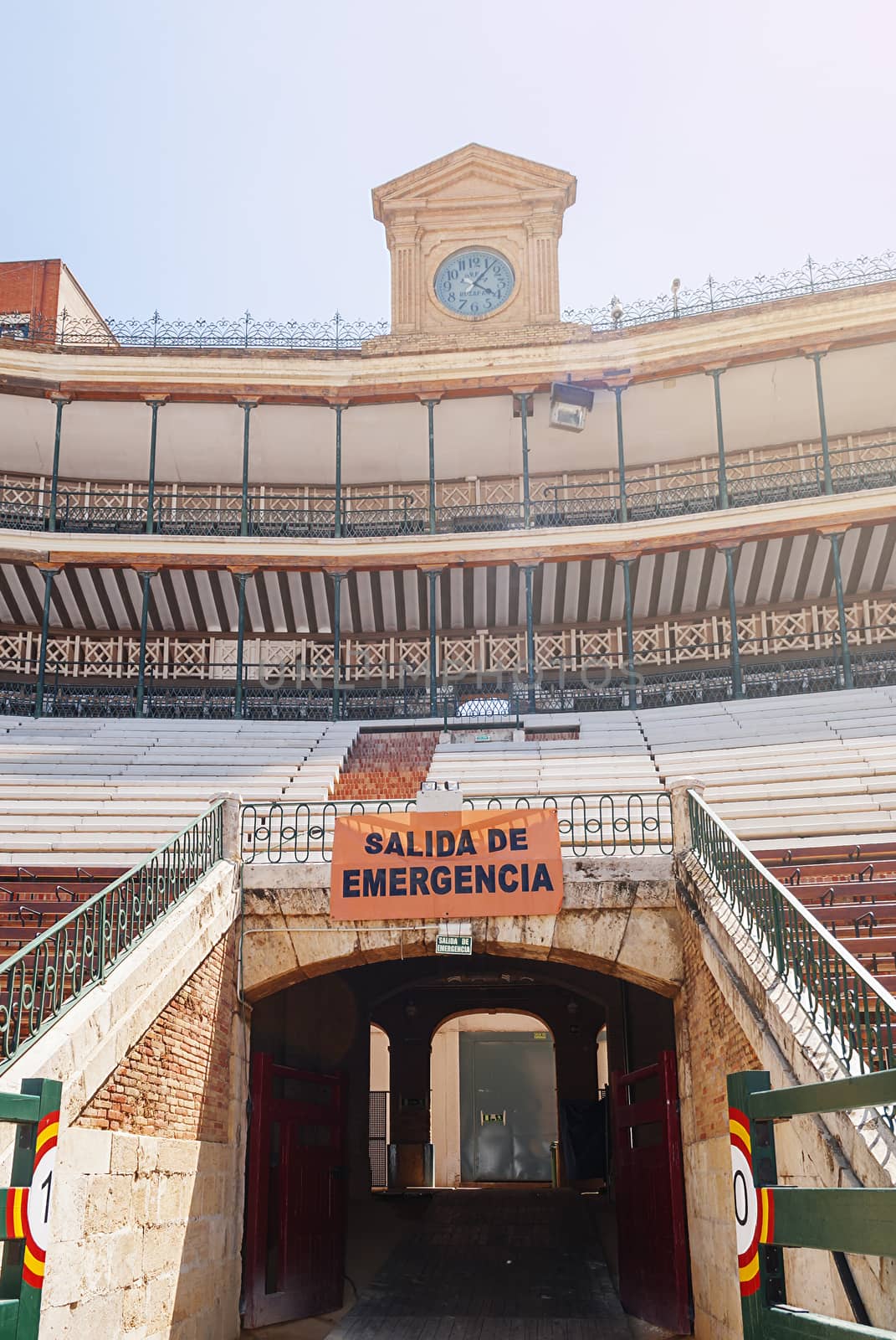 view of the stands with an emergency exit and the ancient clock of a Spanish arena