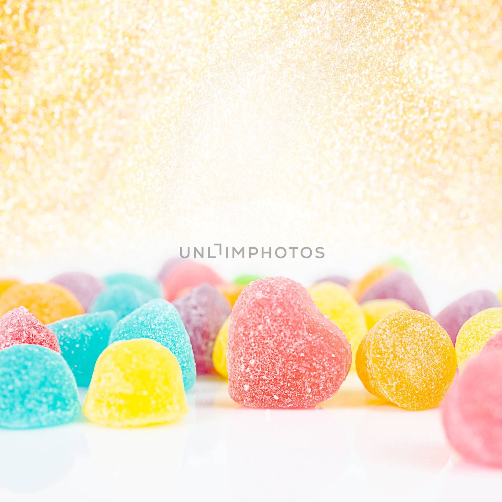 Colorful sugar candies on golden bokeh background.