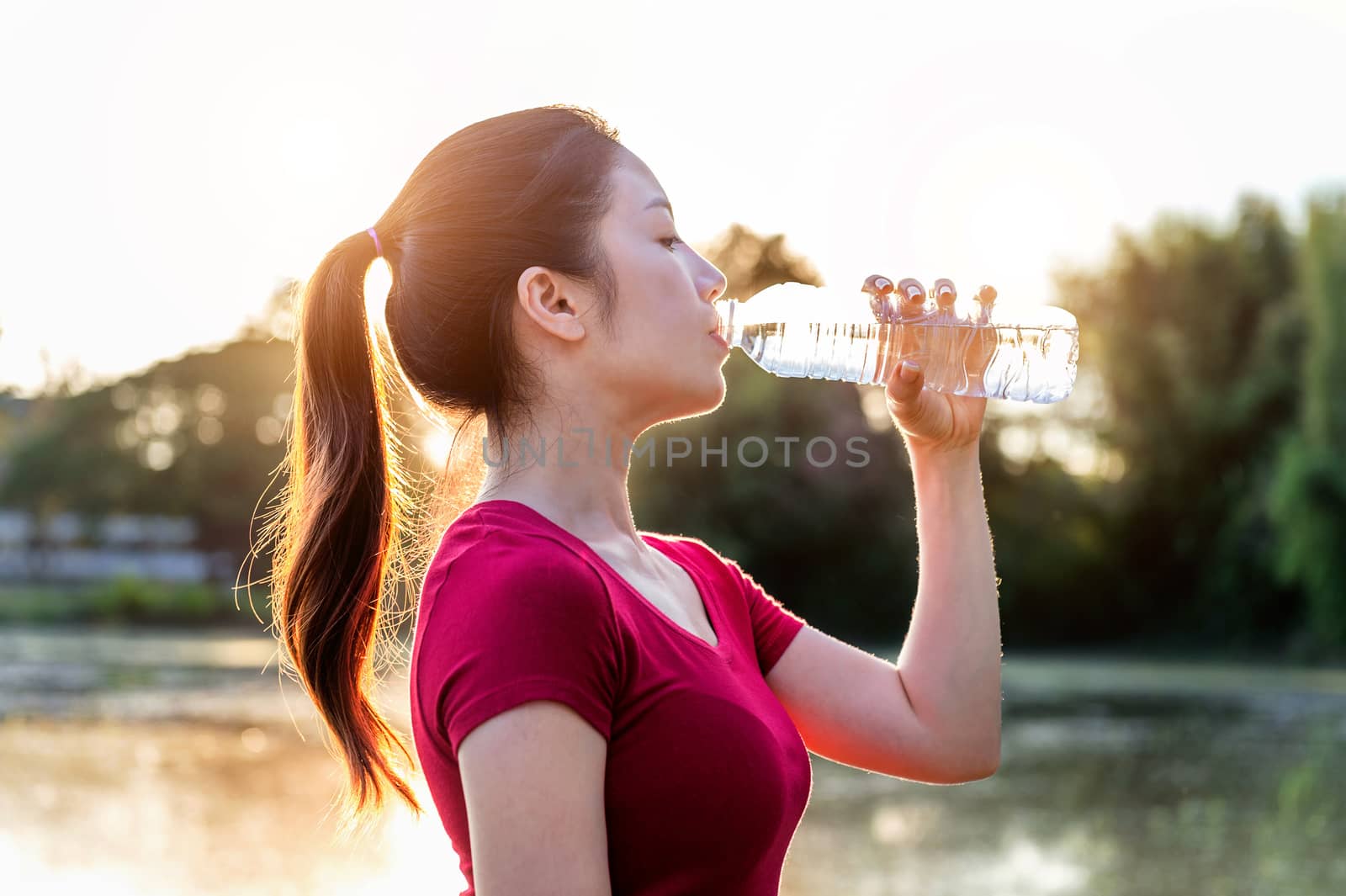 Sporty woman drinking water on sunlight. by gutarphotoghaphy
