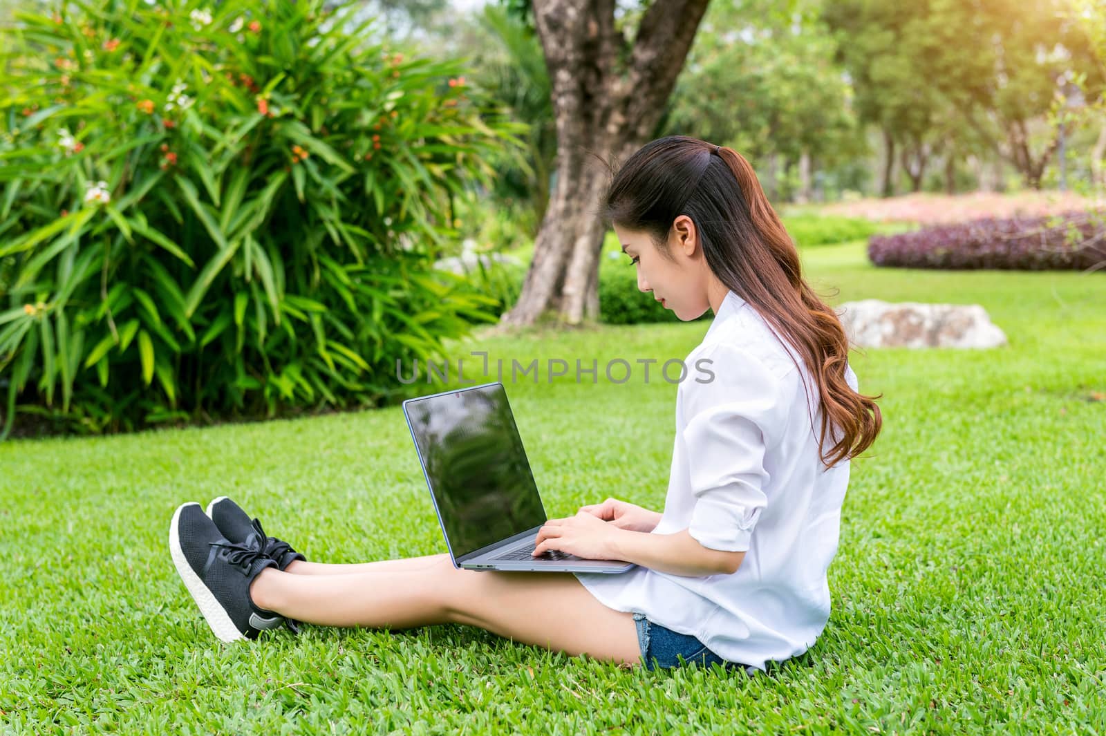 Young woman using laptop in park.