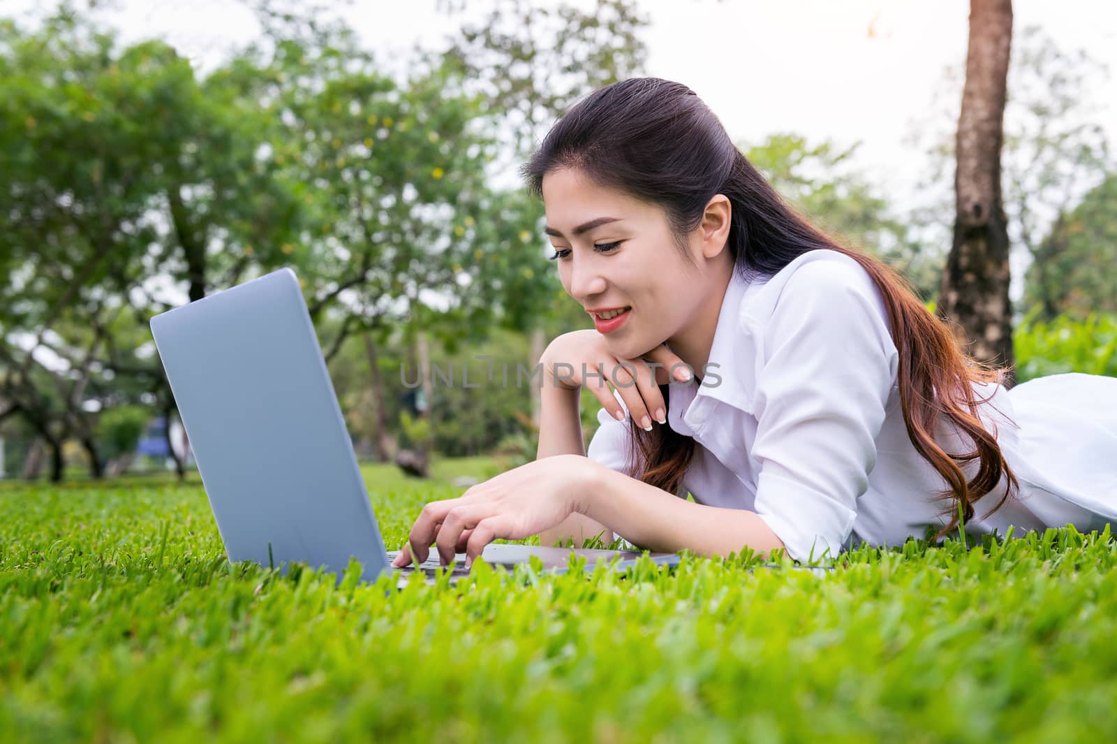 Young woman using laptop in park. by gutarphotoghaphy