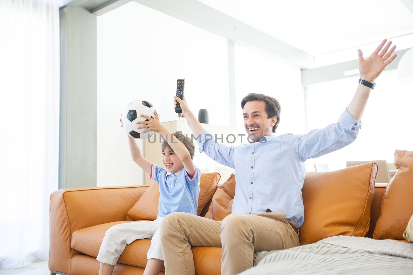 Boy watching soccer match with father by ALotOfPeople