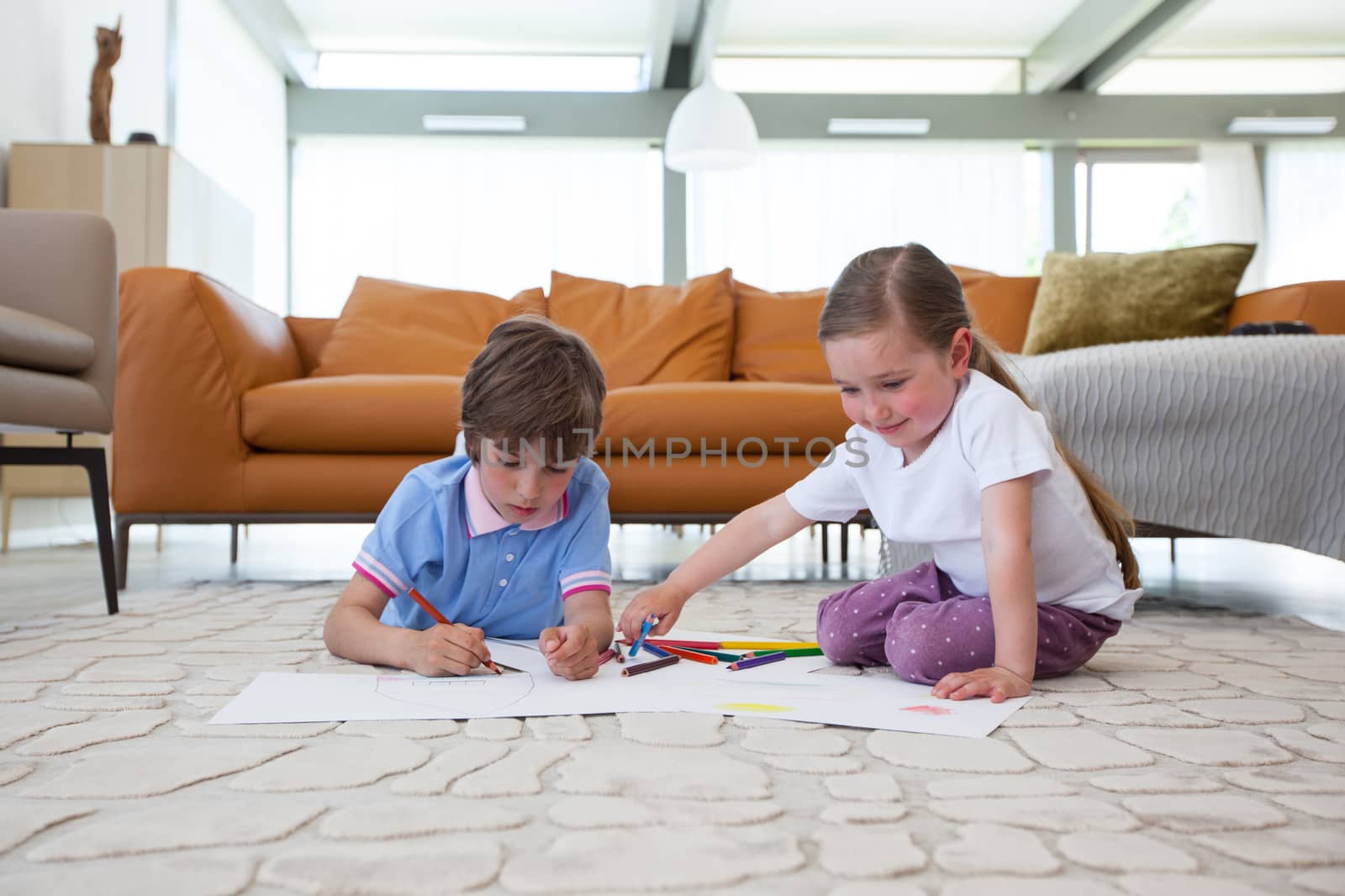 Little boy and girl drawing with color pencils on the floor playing together