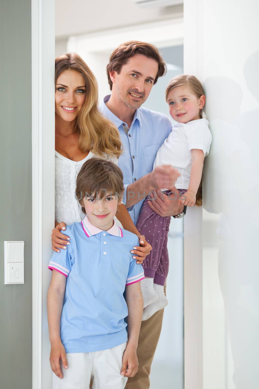 Portrait of happy smiling family with little children in doorway