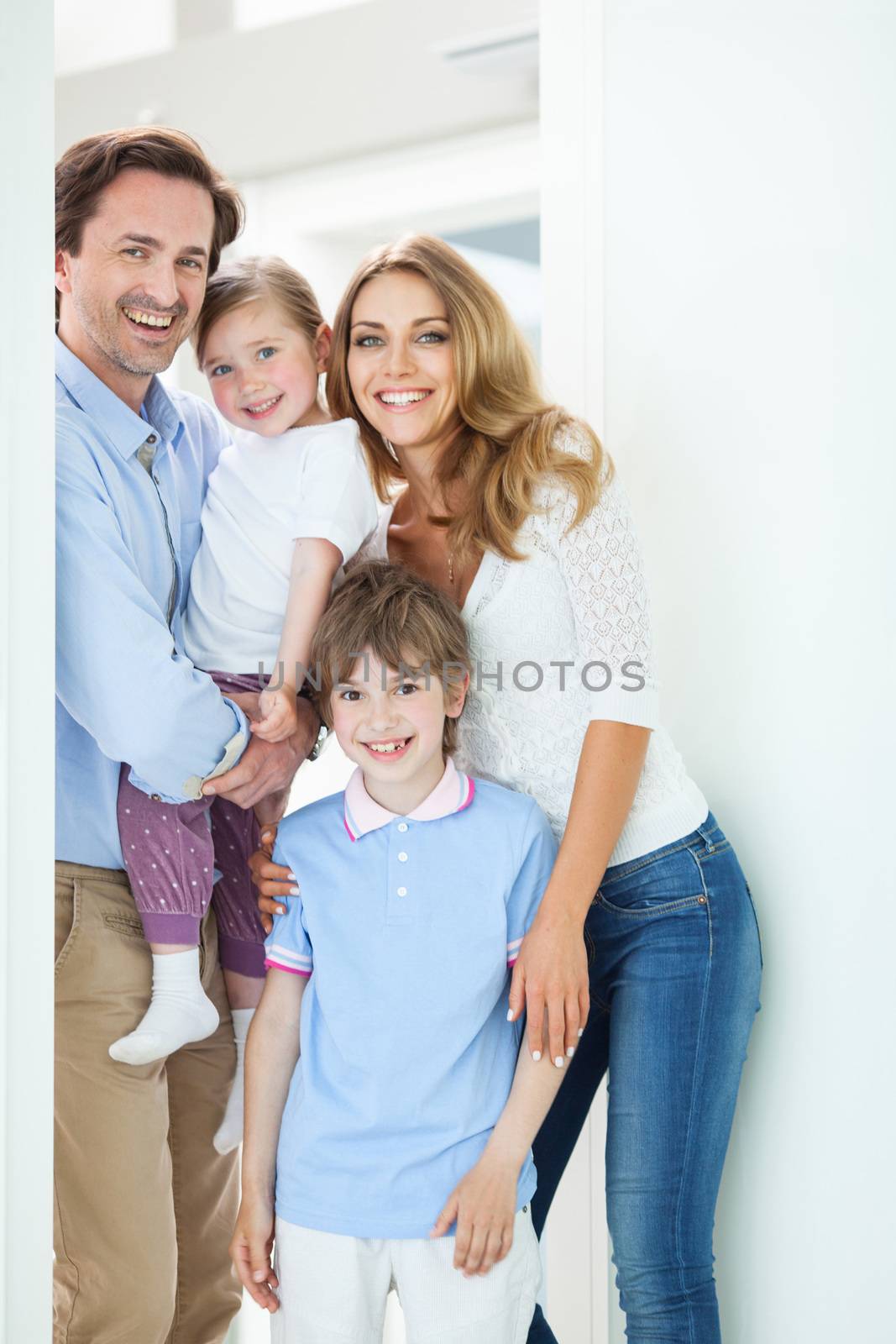 Portrait of happy smiling family with little children in doorway