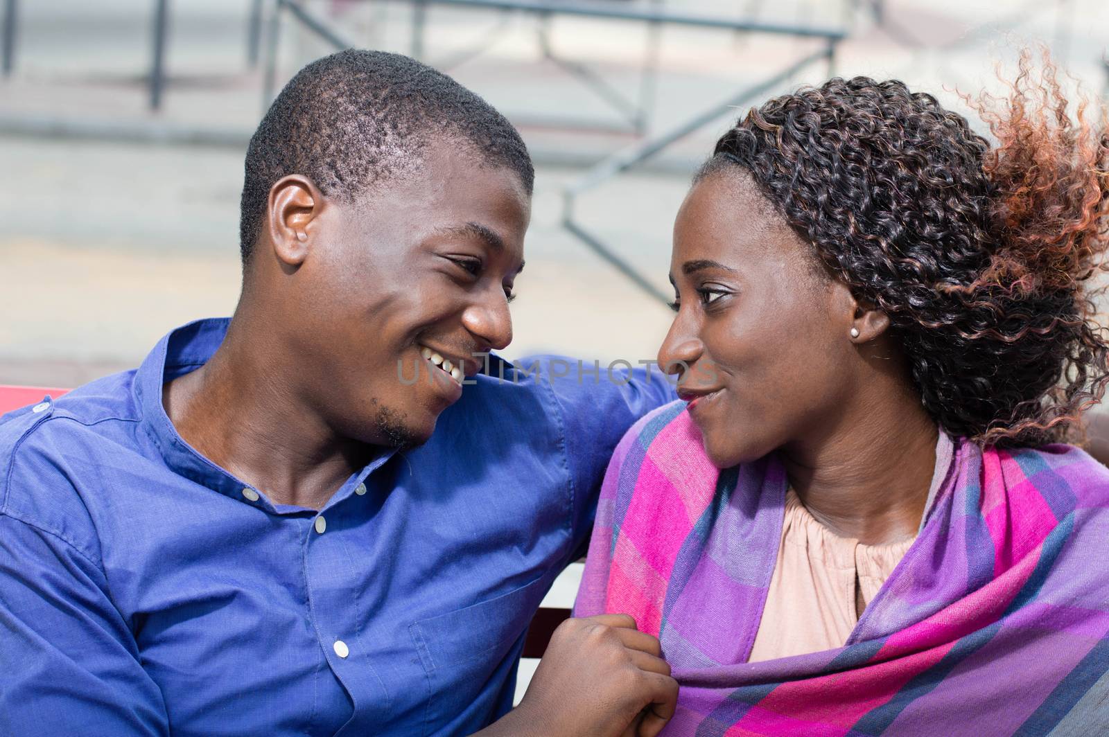 These young people sitting face to face, look  into their eyes with a smile.