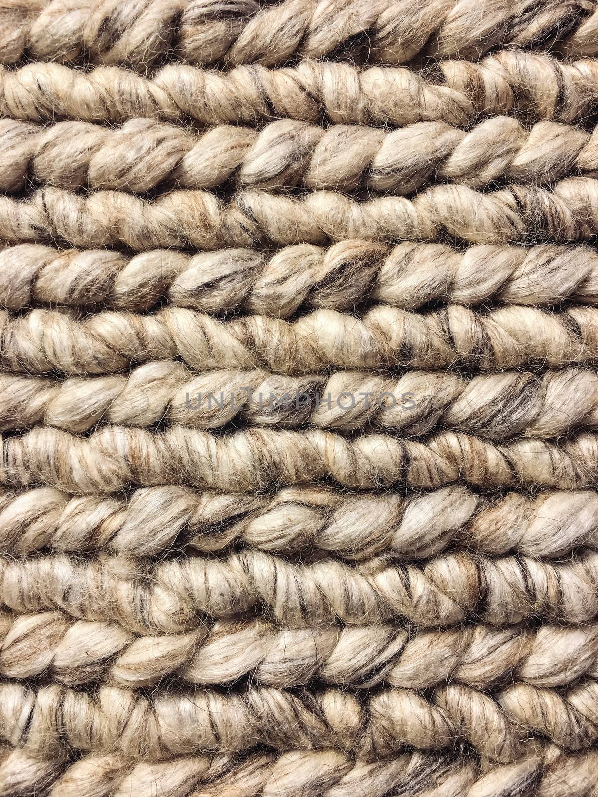 Detail of a handmade chunky knitted rug. Rustic wool background.