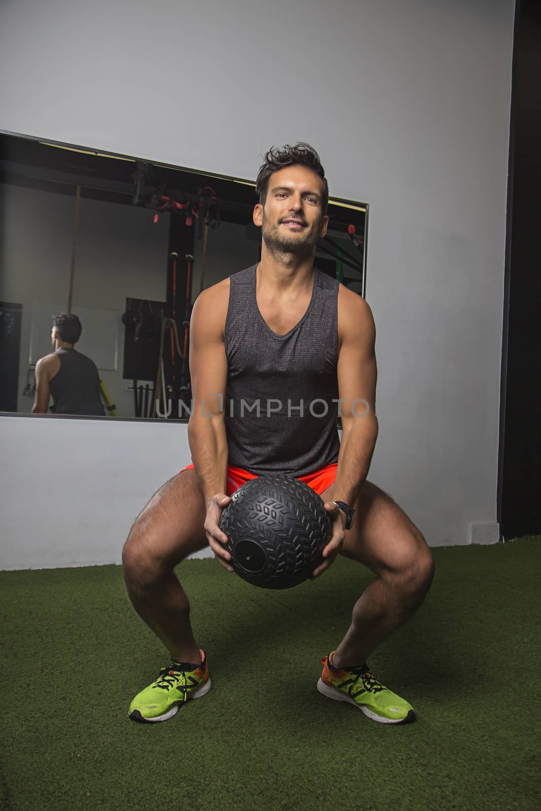 young man pulling up a black medicine ball as part of a slam ball exercise