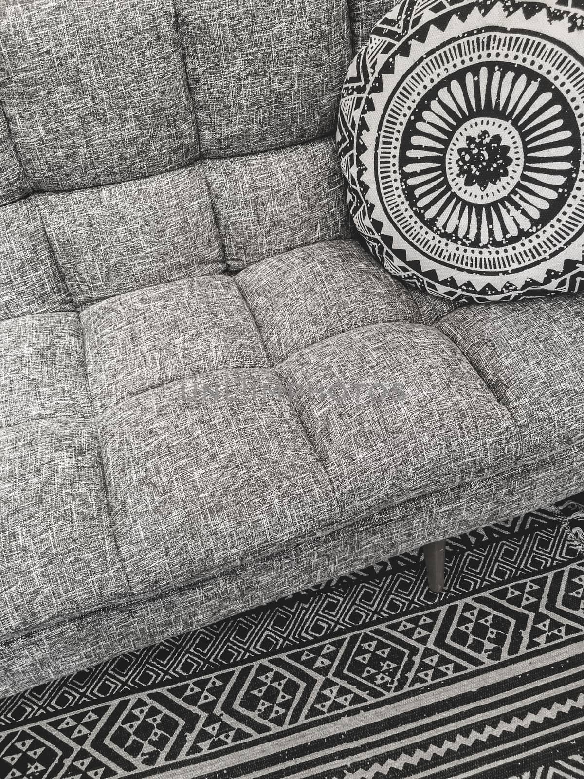 Beautiful interior design in gray tones. Sofa, round cushion and decorative rug.