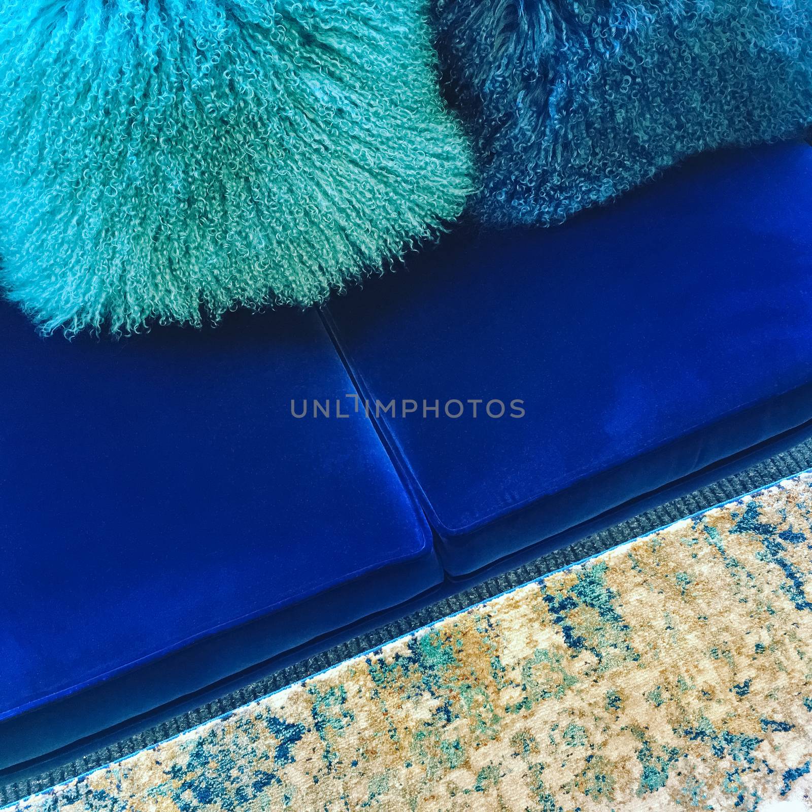 Luxurious sheepskin cushions decorating a blue velvet sofa.