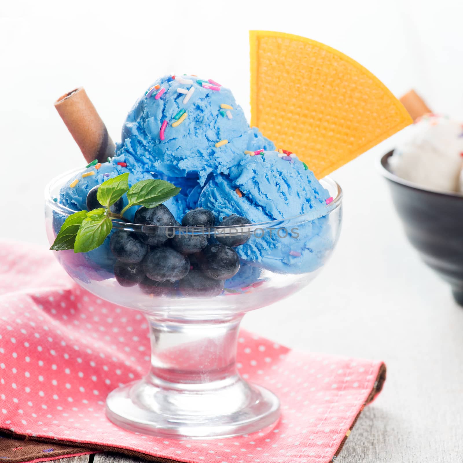 Blue ice cream in cup with blueberry fruits.