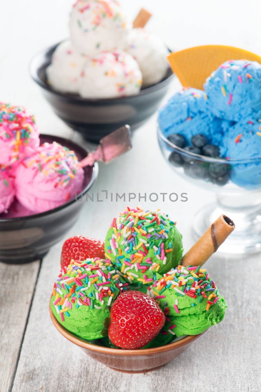 Various flavor ice cream in bowl on wooden background.