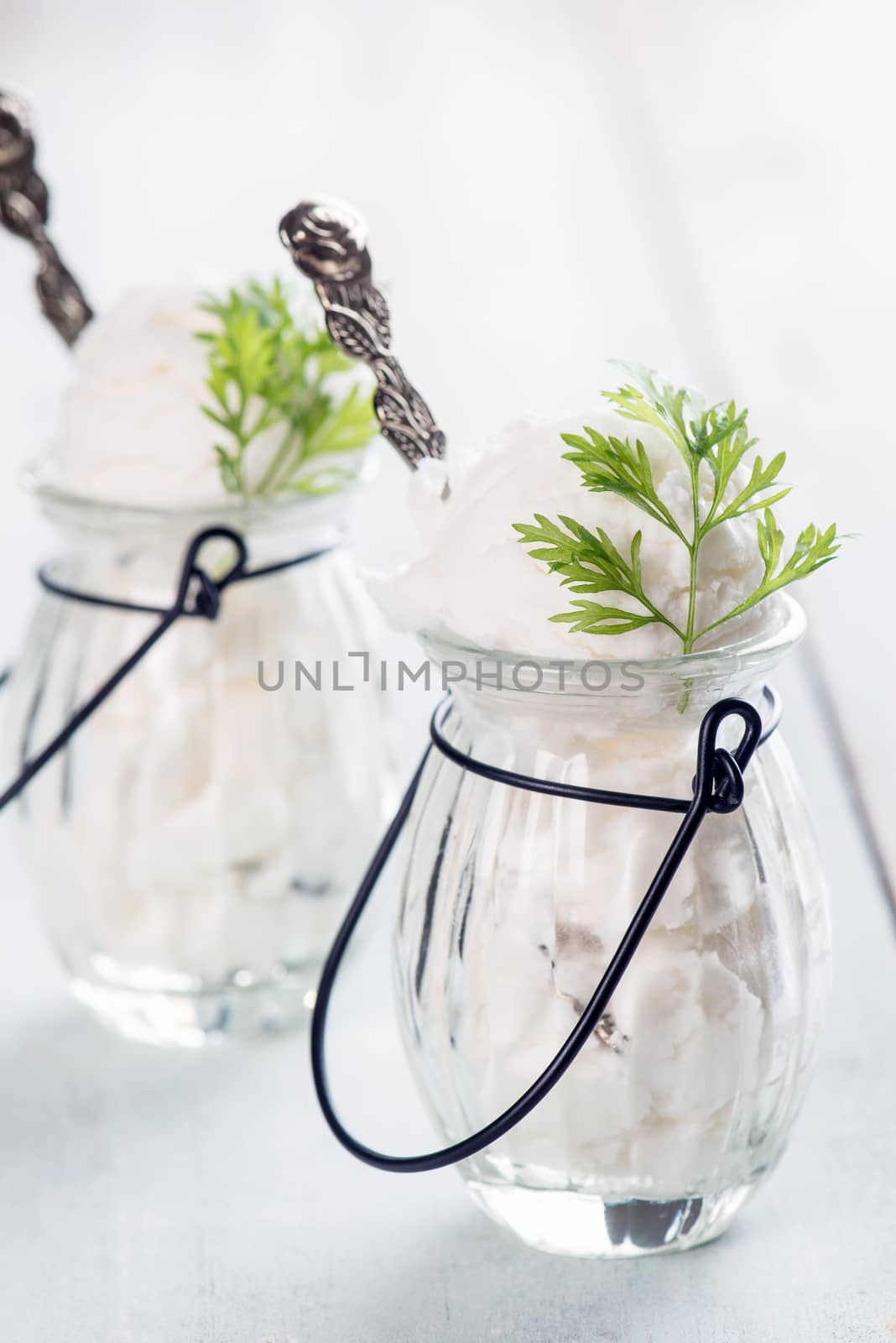 White ice cream in cup on bright rustic wooden background.