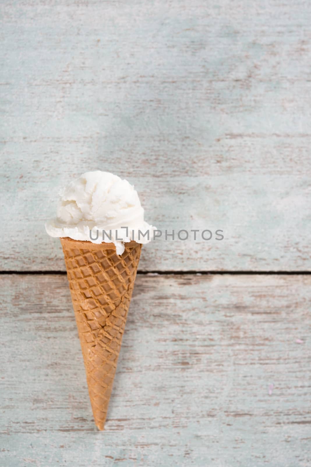 Top view white ice cream wafer cone on bright rustic wooden background. With copy space.