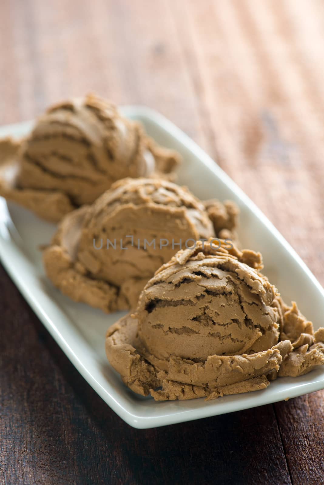 Chocolate ice cream in plate on dark wooden background.