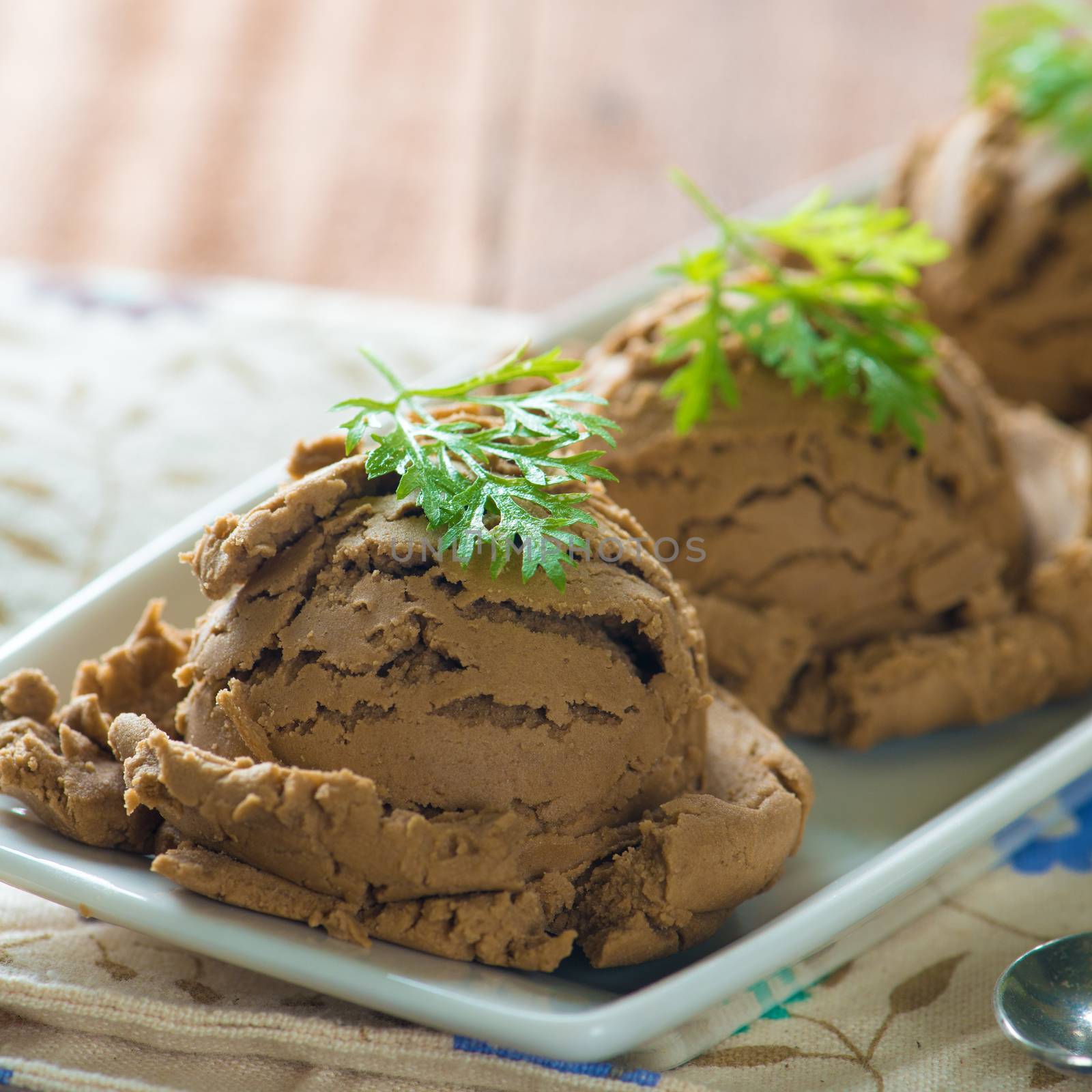 Brown ice cream in plate on dining table background.