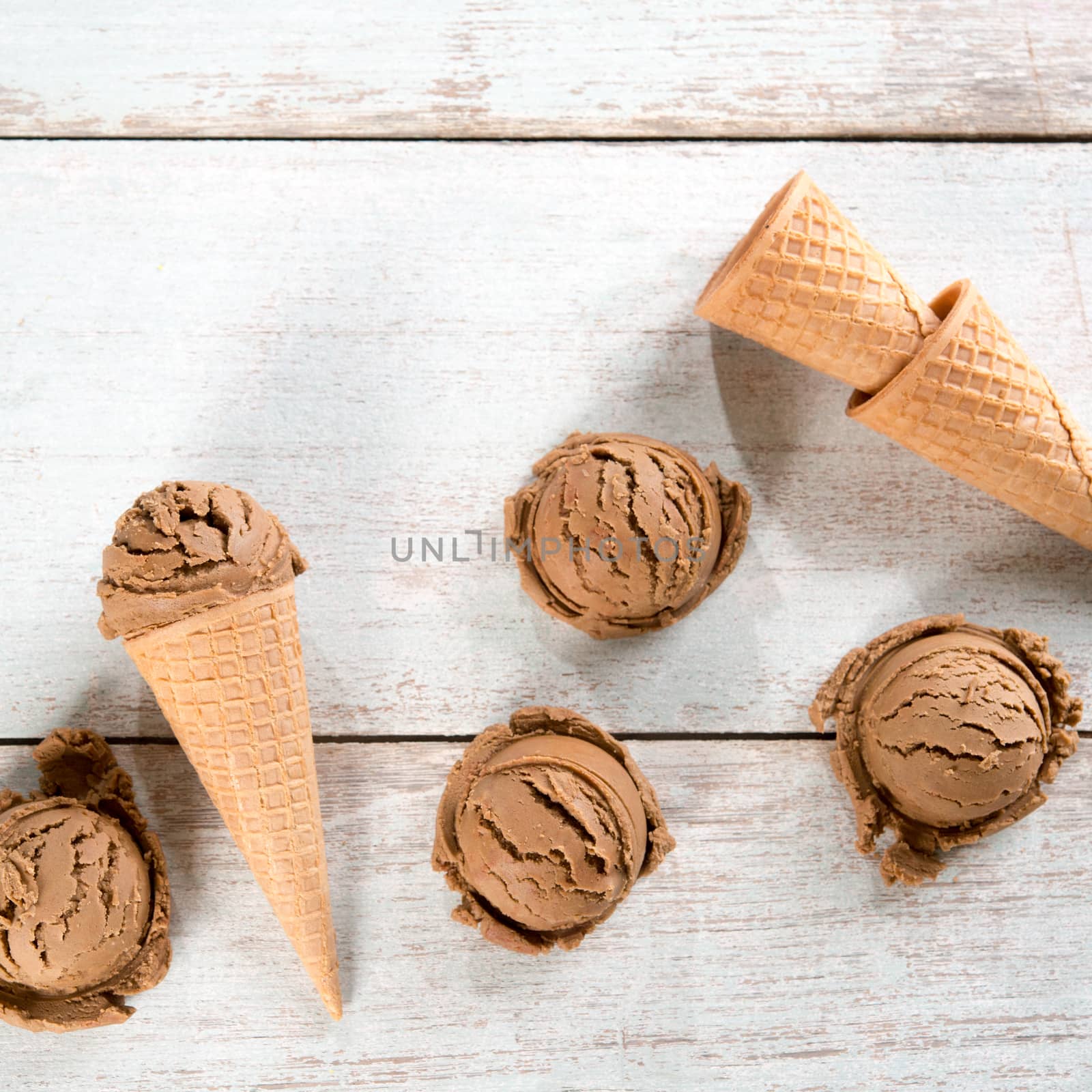 Top view chocolate ice cream in waffle cone on rustic wooden background. Copy space on above.