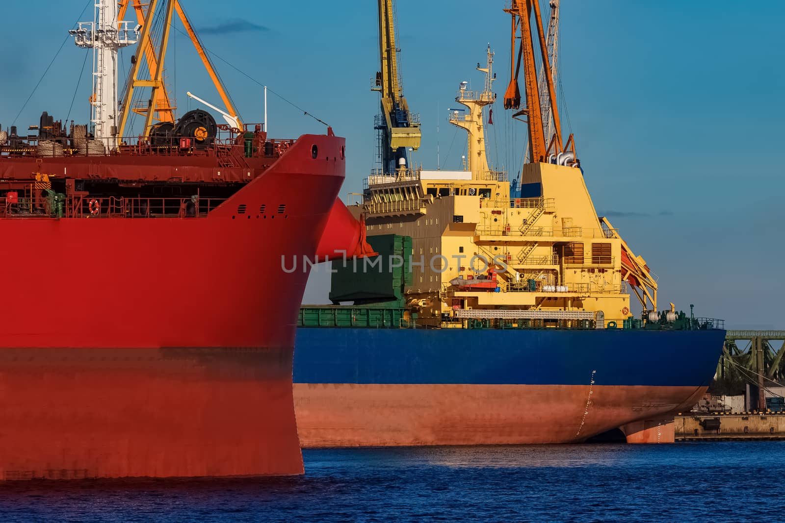 Red and blue cargo ship loading in the port of Riga