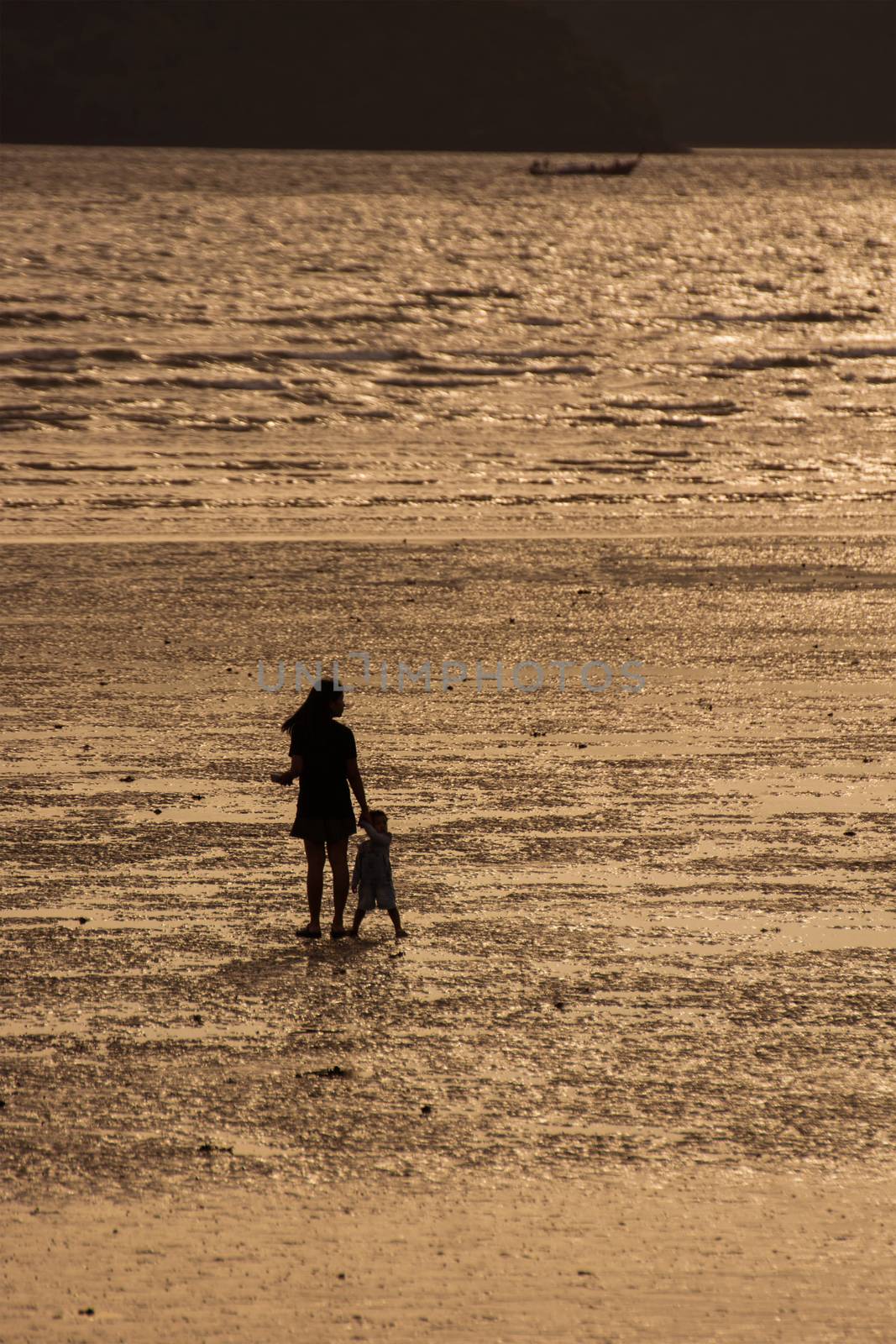 Silhouettes Of Mother And Son On Beach At Sunset.